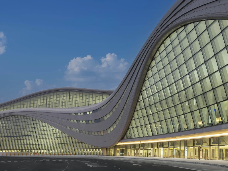 glass-fronted Zayed International Airport exterior at dusk, UAE