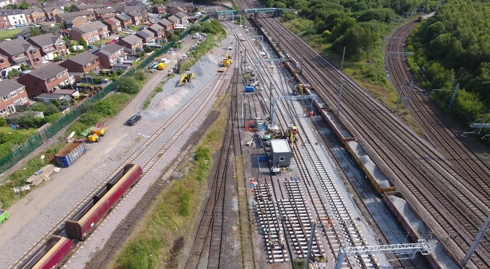 Aerial view of a railway depot with multiple train tracks, construction work and nearby residential houses
