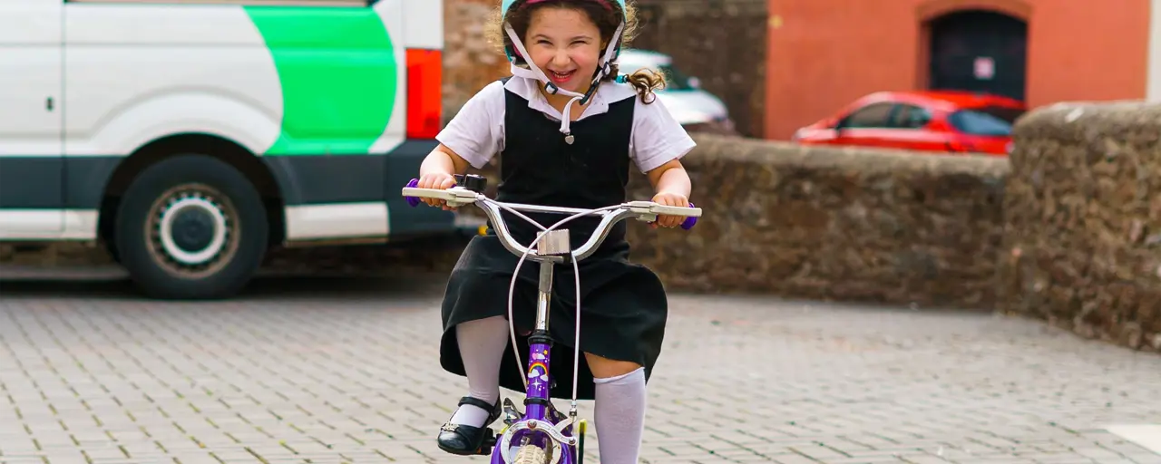 A smiling female child riding on a bicycle