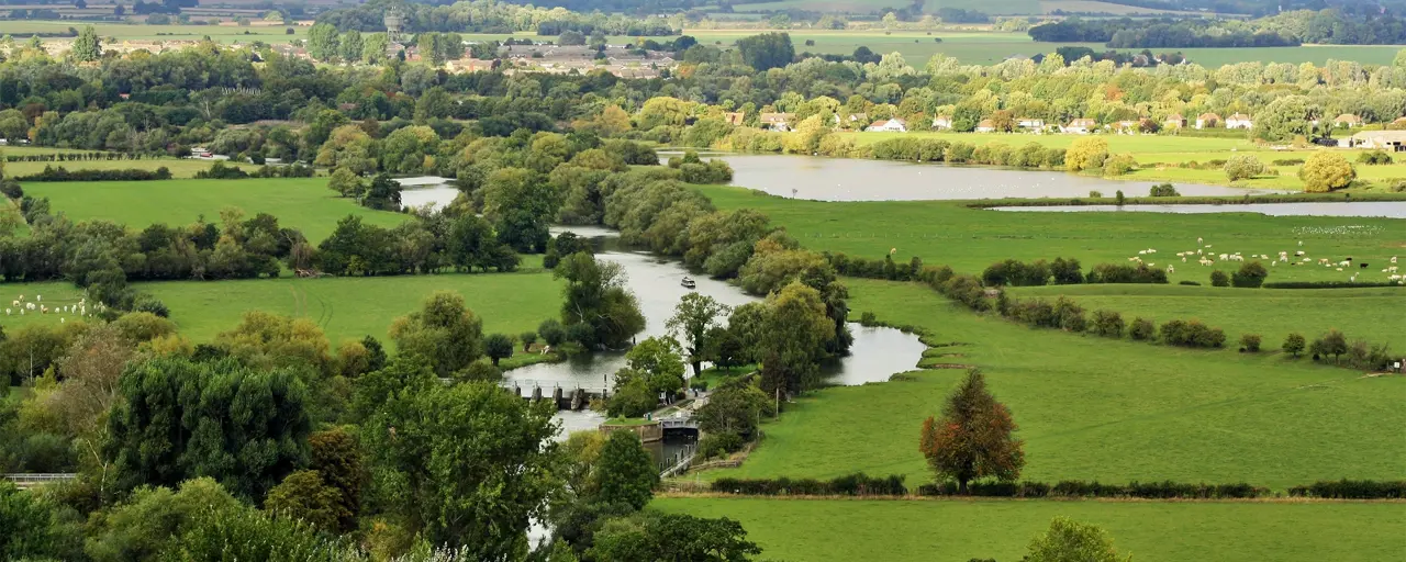 Aerial view of water in amongst a green landscape of fields and farmland