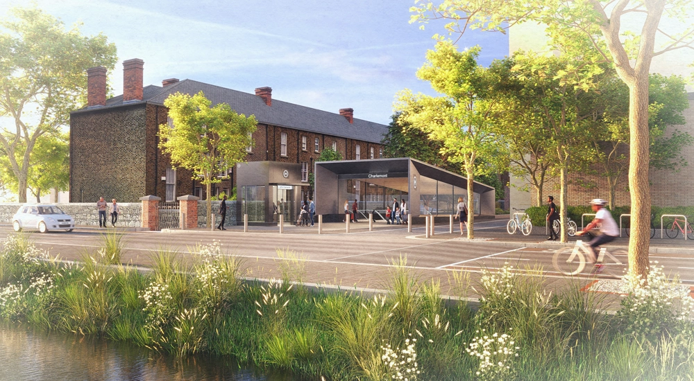 The entrance to a modern metro station, next to brickwork buildings and with a background of trees.