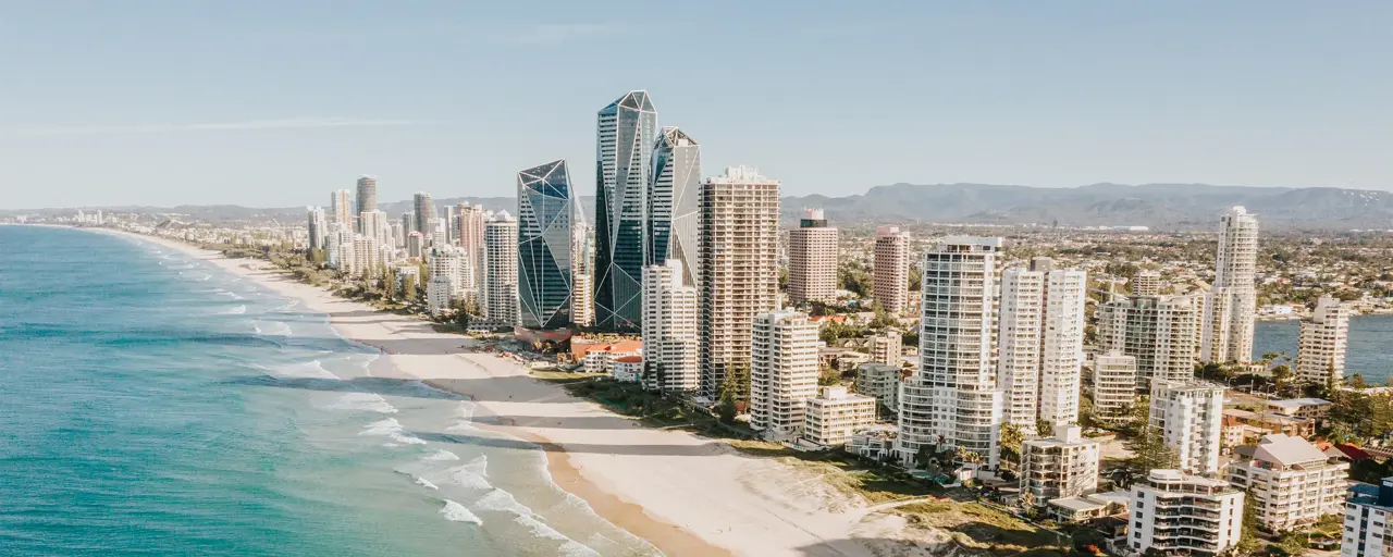 View of a long sandy beach with blue sky and skyscrapers on the shoreline