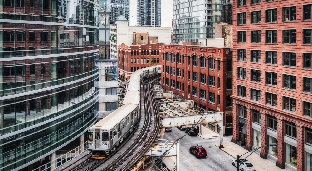 A train moving on tracks in between buildings in Chicago