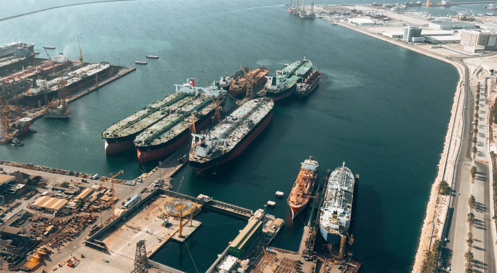 Image of maritime boats pulling up to harbor, with blue sea.