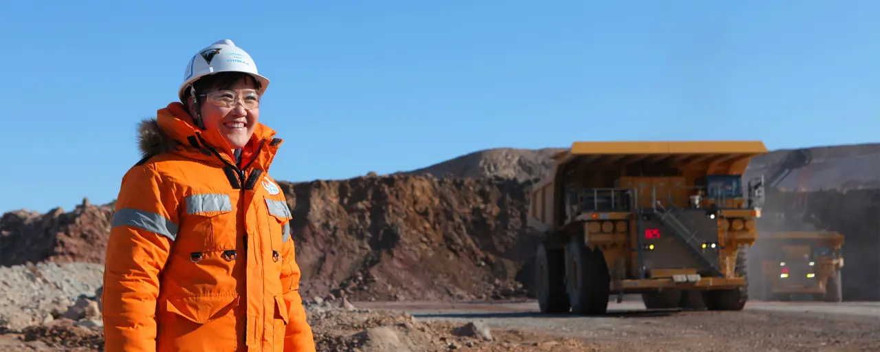 Woman in bright orange construction site uniform standing in a sandy landscape
