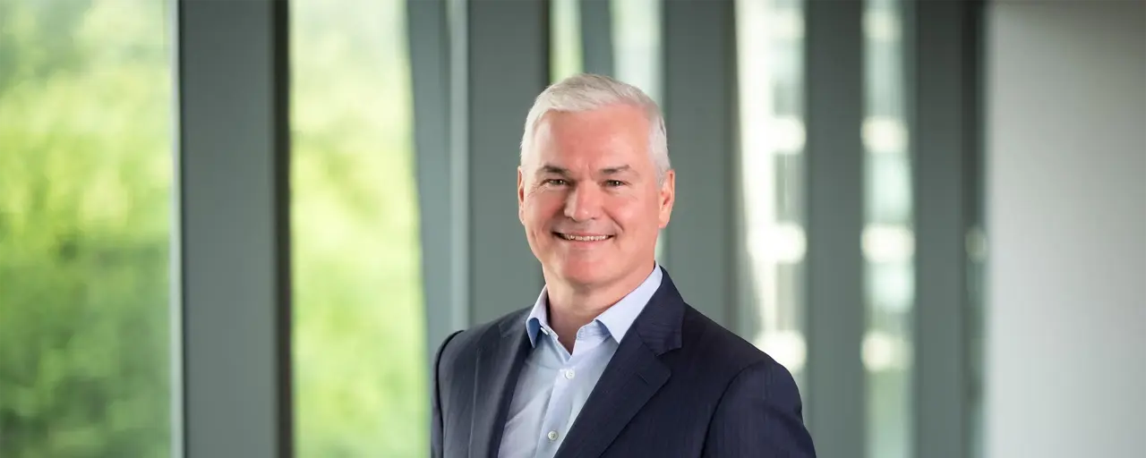 Vincent Clancy, CEO, smiling in front of a window with trees behind him