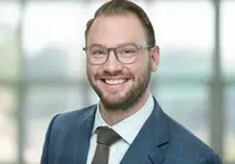 Portrait of Maximilian Frisch, Associate Director, in front of a glass office building