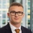Portrait of Daniel Foreman, Associate, standing in window based office building smiling.