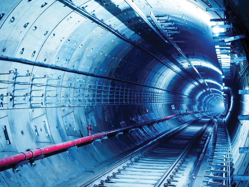 Underground transit tunnel with railway tracks illuminated by blue light