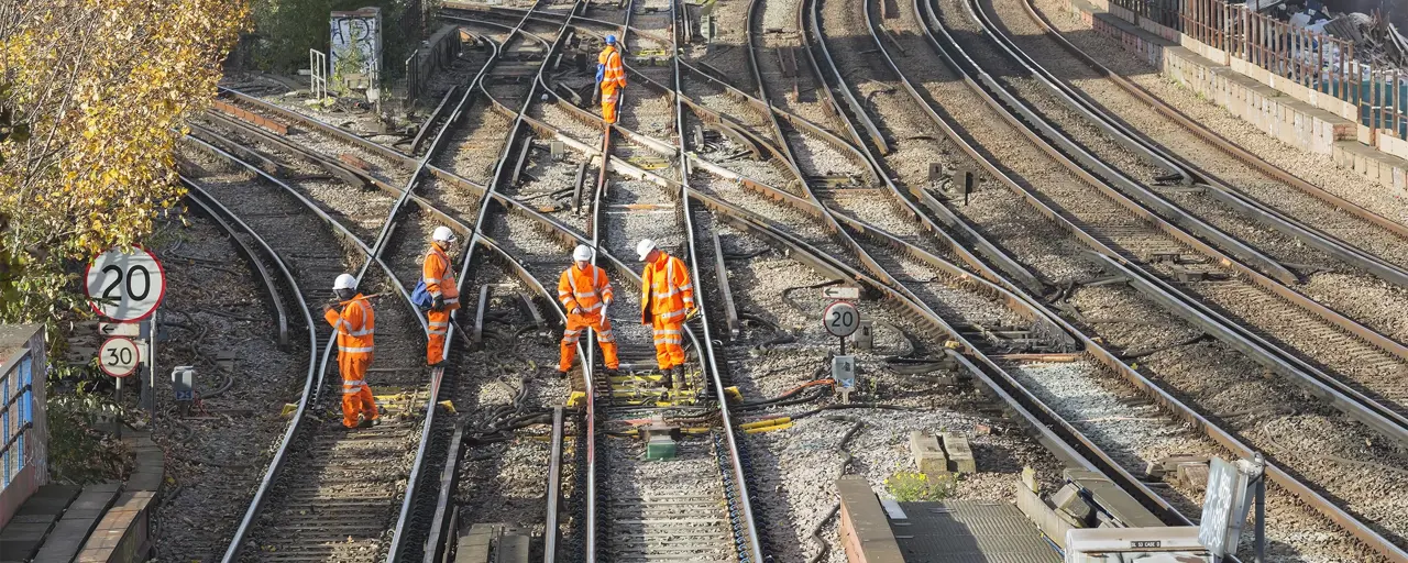 Construction workers in hard hats and high-vis gear on train tracks