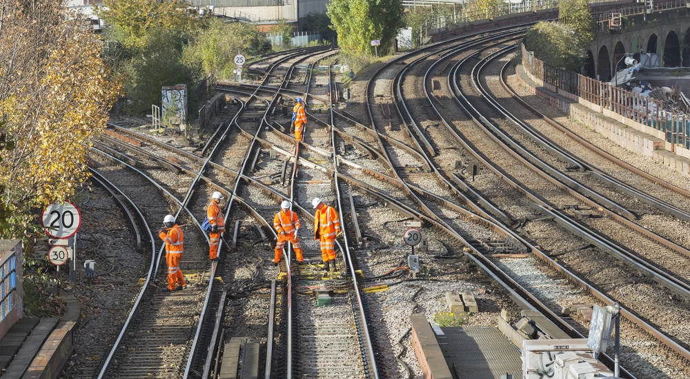Construction workers in hard hats and high-vis gear on train tracks