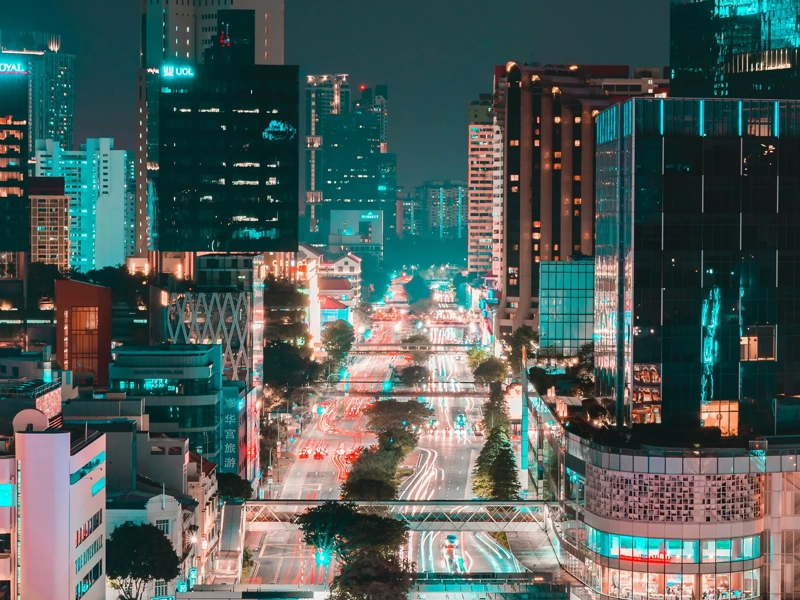Singapore at night with glass skyscraper buildings and brightly lit roads with traffic