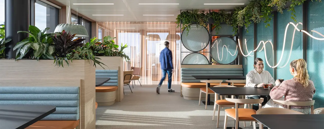 A group of people in a modern office furnished with plants and colourful furniture