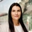 Portrait of Tiffany Emmett, Associate Director, Construction Economics, standing outside in front of buildings featuring an urban cityscape with a mix of architectural styles. The scene includes some windows and red features, adding a touch of color.