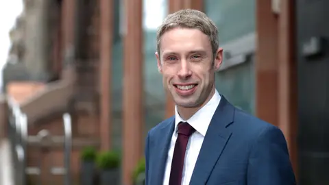 Portrait of Paul Convery, Director, Forensic Planning & Delay, UK, outside in front of brown buildings