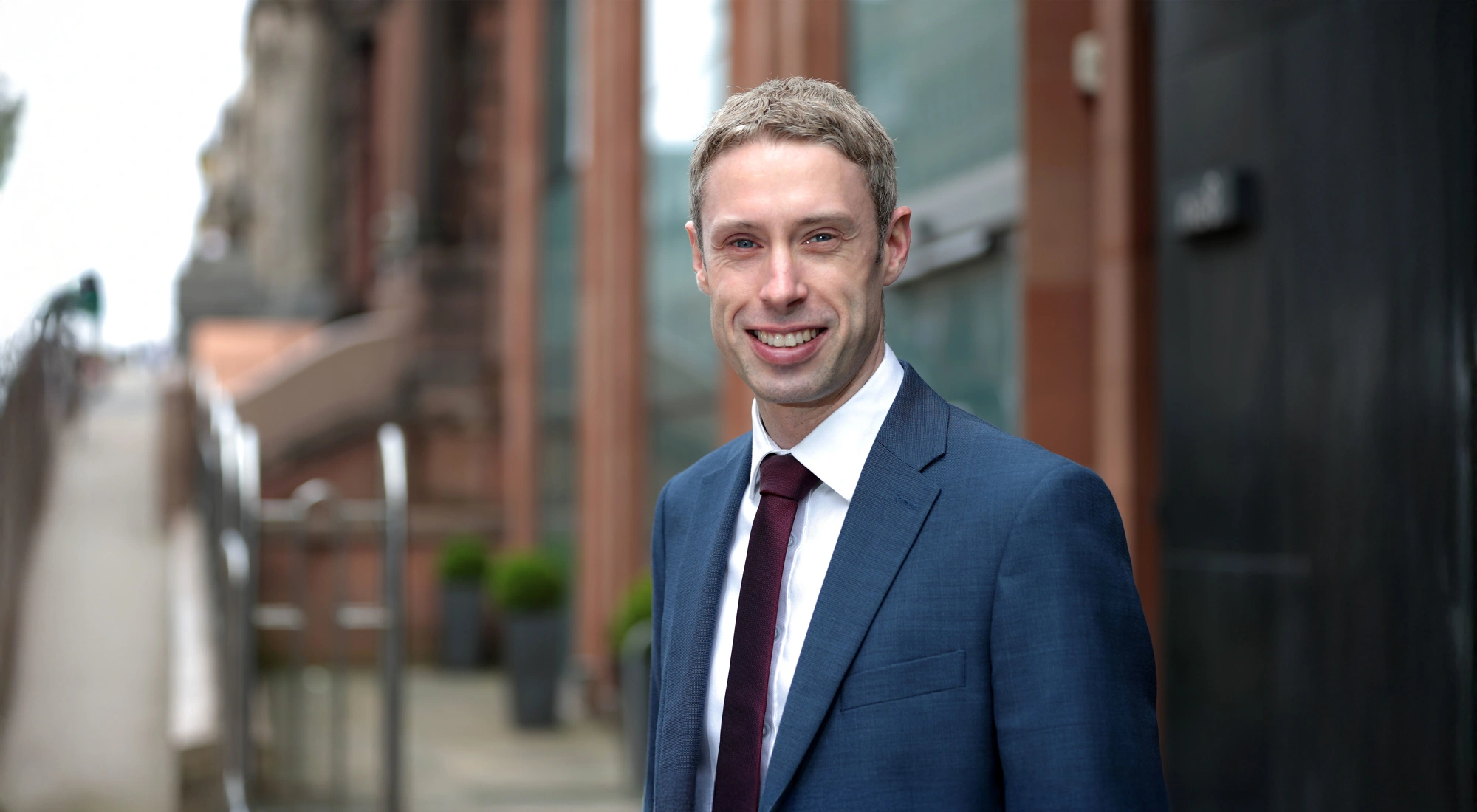 Portrait of Paul Convery, Director, Forensic Planning & Delay, UK, outside in front of brown buildings