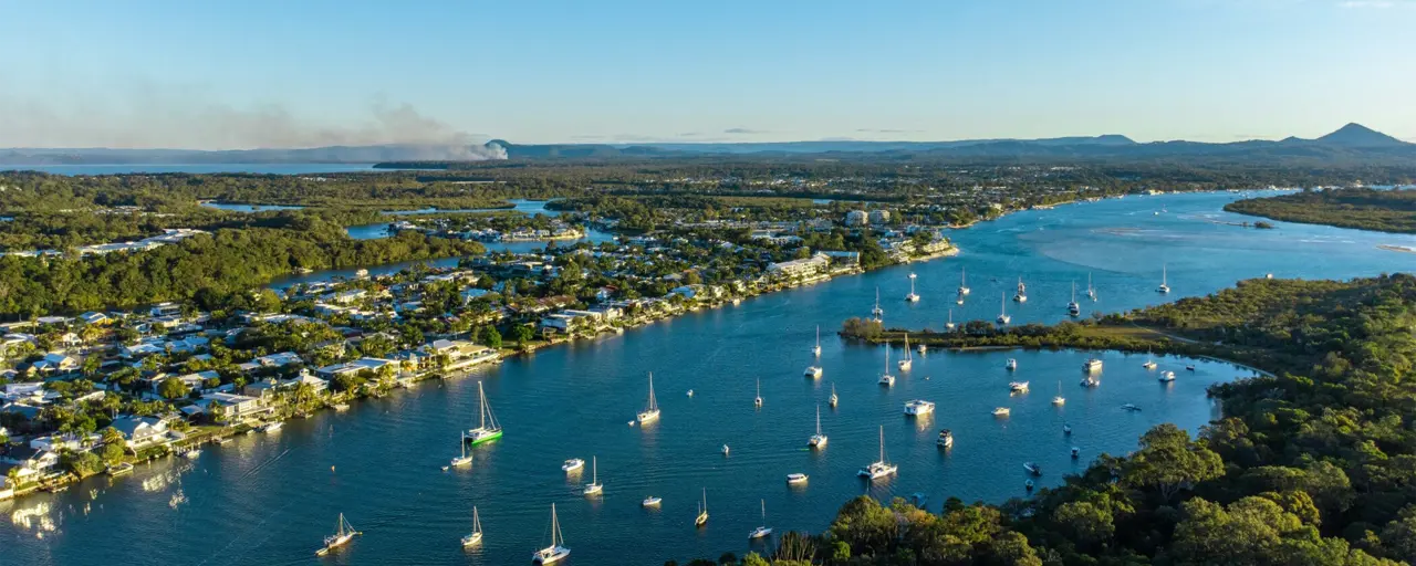 Large lake with sailing boats and water front housing with blue skies