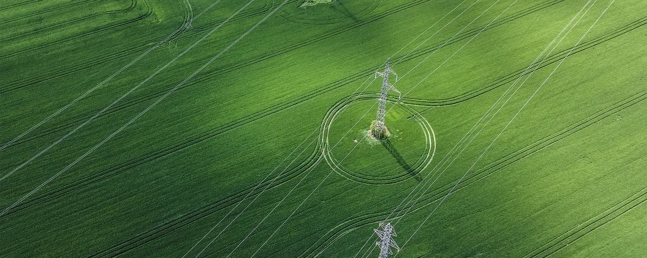 Aerial view of of green field and overhead electricity lines