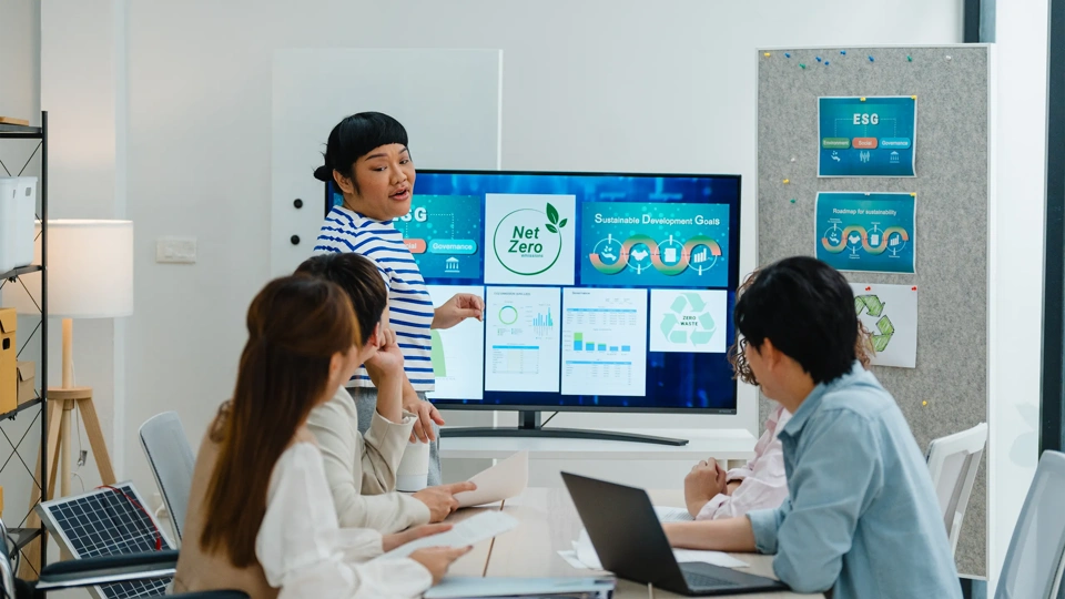 A group of coworkers discuss renewable energy solutions, emphasizing sustainable business practices in a modern office setting.