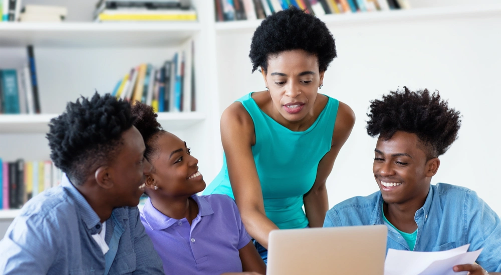 Group of four gathered around laptop smiling
