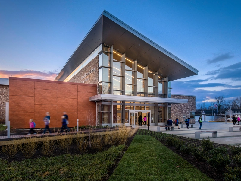 Exterior photo of a standalone library building with groups of people entering and exiting