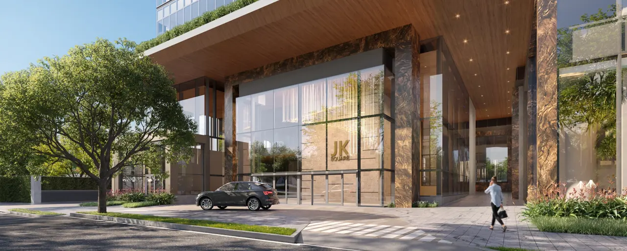 Entrance to a modern, glass building with a tree in the foreground on a sunny day