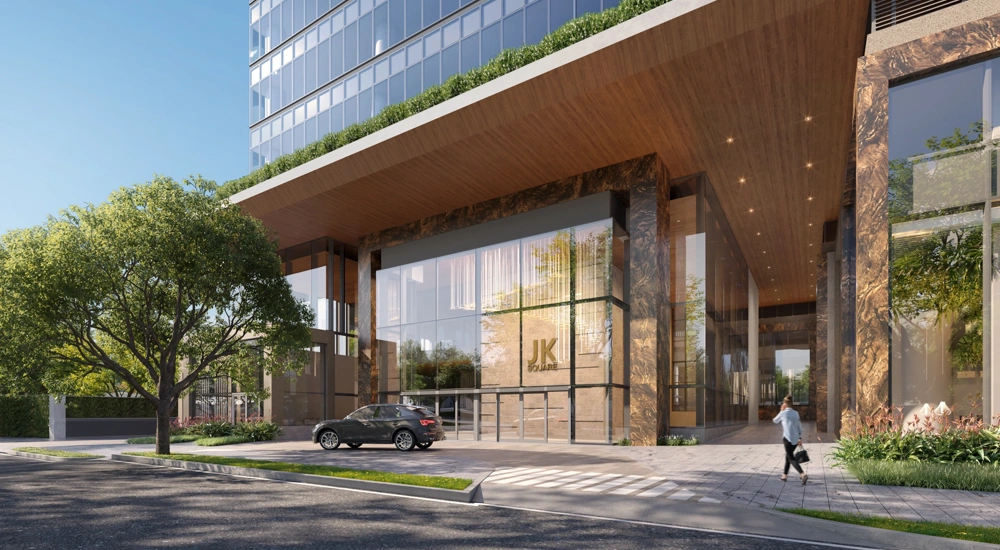 Entrance to a modern, glass building with a tree in the foreground on a sunny day
