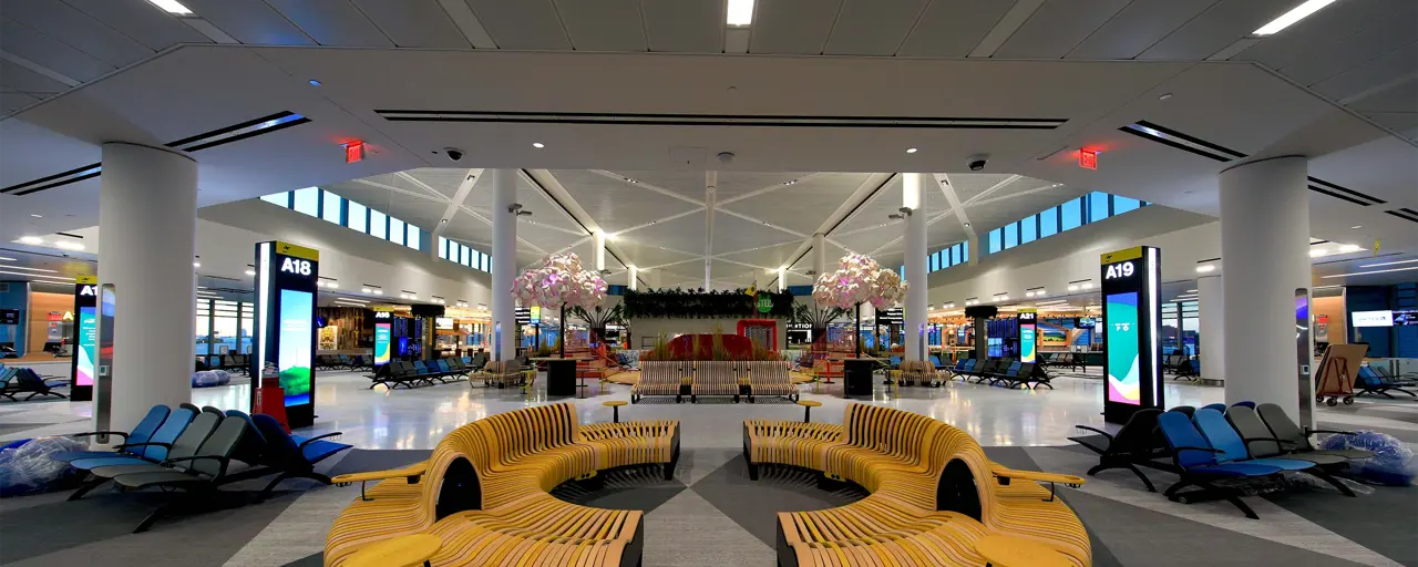 Interior photo of an airport lounge with bench seating in the foreground