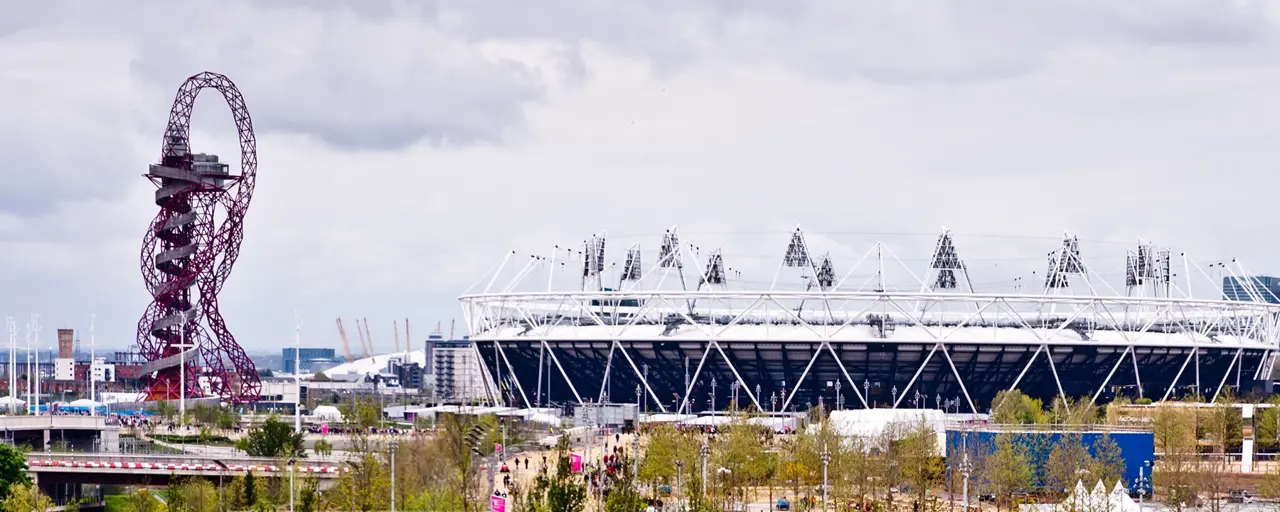 Sports stadium exterior surrounded by fun fair and rollercoaster 