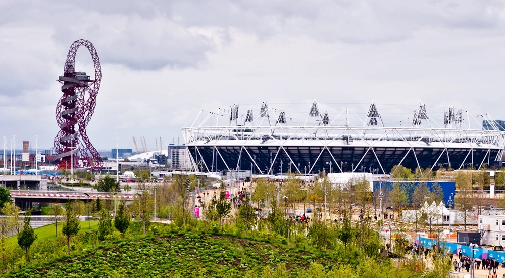 Sports stadium exterior surrounded by fun fair and rollercoaster