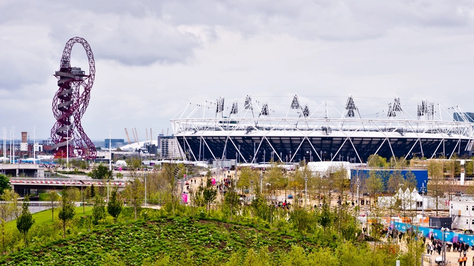 Sports stadium exterior surrounded by fun fair and rollercoaster