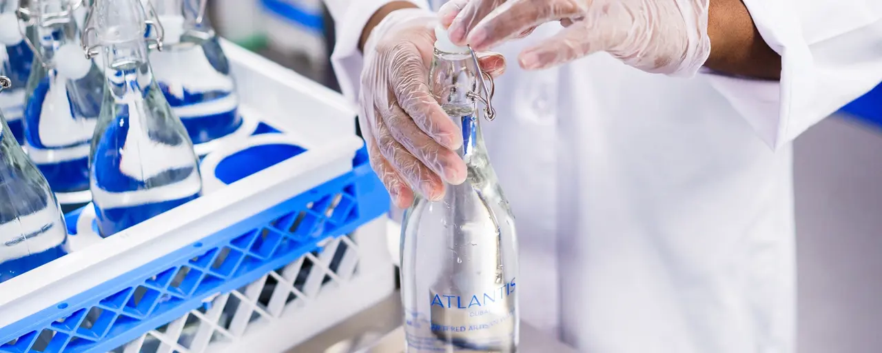 Factory worker in white lab coat bottling water