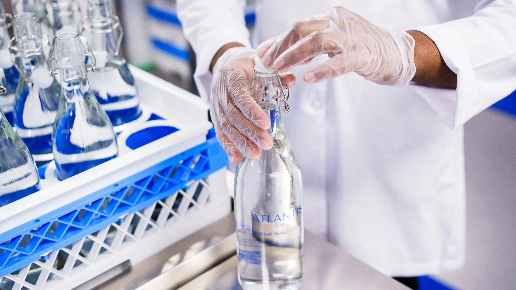 Factory worker in white lab coat bottling water