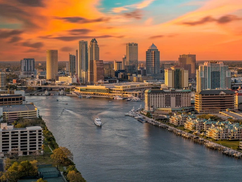 Ariel view of city skyline at sunset with boats on river.
