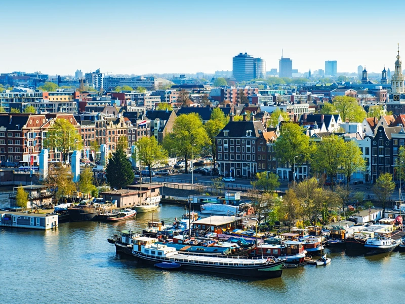 Aerial View of Amsterdam city on One Beautiful Sunny Day. View of Amsterdam rooftops, also visible are many bridges, harbor, boats, yachts, canals, restaurants, bikes, churches and typical dutch houses in Centrum. Amsterdam, Netherlands.
