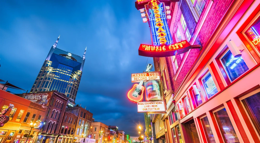 Low shot view of city with pink and orange neon lights on building.