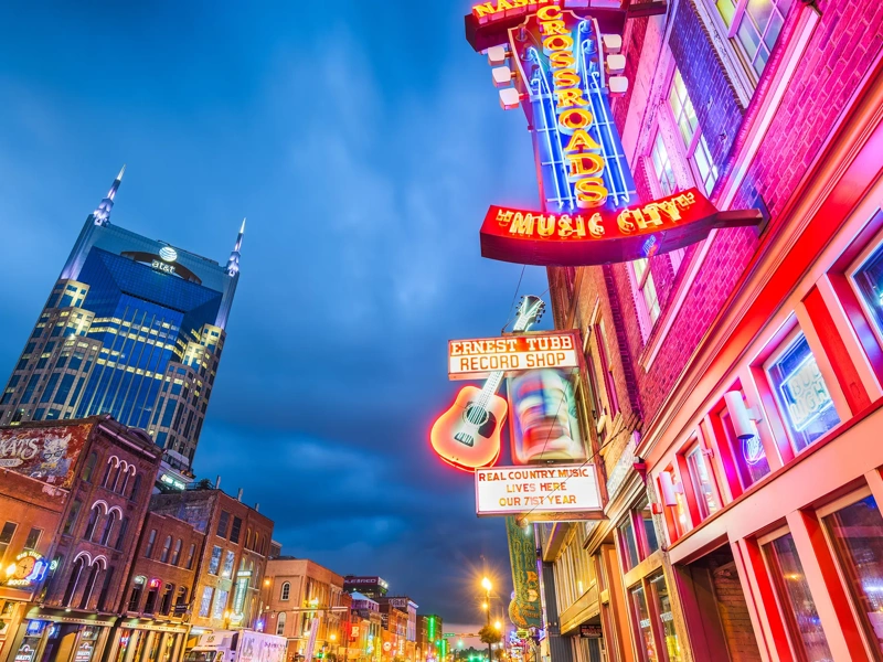 Low shot view of city with pink and orange neon lights on building.