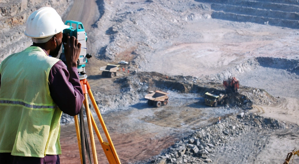 Builder looking into machine overlooking empty grovel construction site