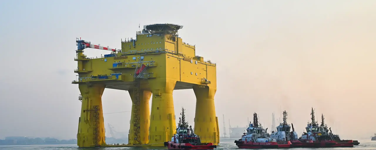 The DolWin epsilon converter station (an solid, yellow structure) floating in the sea.  