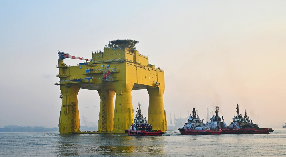 The DolWin epsilon converter station (an solid, yellow structure) floating in the sea.