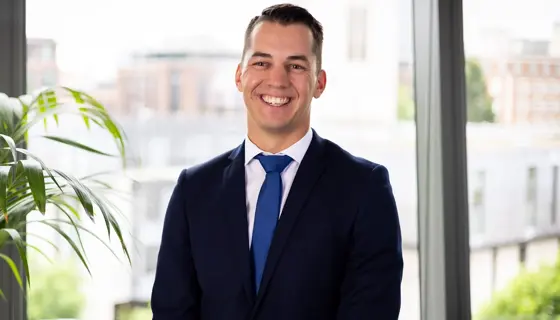 Portrait of Nicolas Offroy, Principal Consultant, Australia, standing in office space against window and plants.