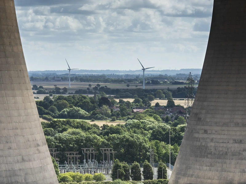 a close up view of the cooling towers at Drax power station showing a wind farm in the distance