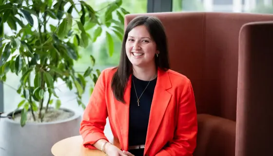 Portrait of Halle Stewart, Associate Director, Asia Regional Sector Lead, Singapore, sitting in office space next to a plant.