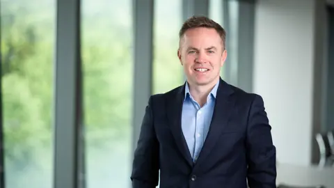 Alan Sinclair, UK Head of Energy and Natural Resources, in an office smiling in a suit