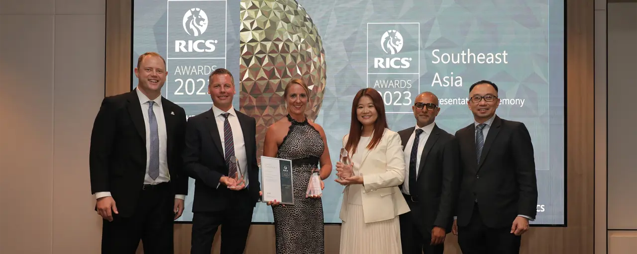 Photo of a group of six people at an awards event with two holding trophies