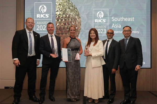 Photo of a group of six people at an awards event with two holding trophies