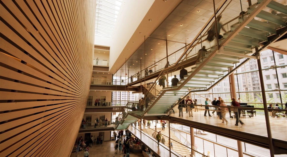 Interior of office building with wood panelling, glass stairs and workers