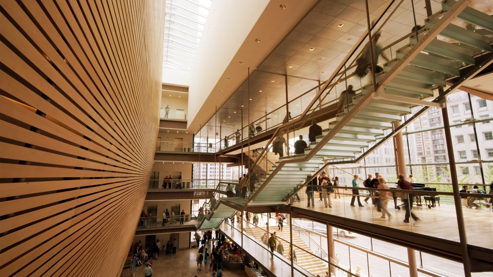 Interior of office building with wood panelling, glass stairs and workers