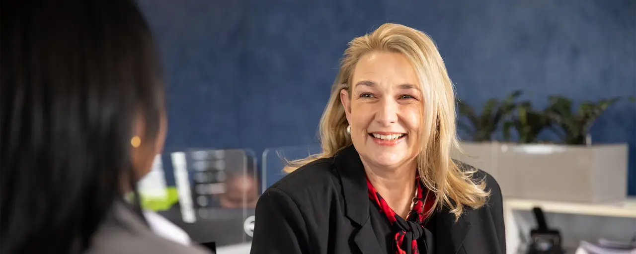 Female employee with blonde hair smiling in office space.