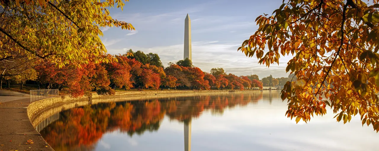 Reflection of statue in water surrounded by autumn trees